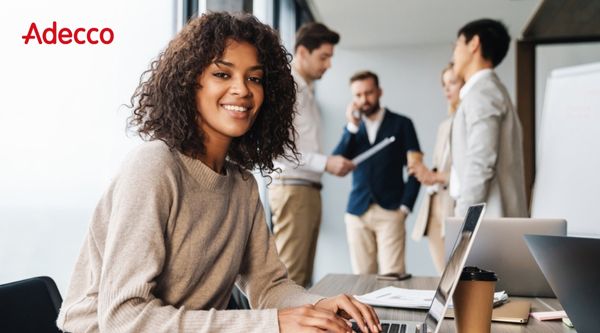 adecco vrouw werk laptop collega's in achtergrond