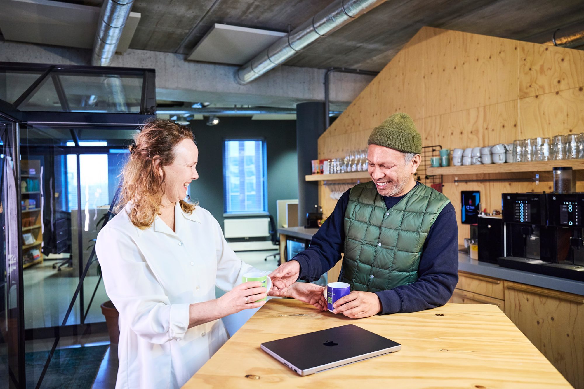 Lachende collega's met koffiemokken in de handen